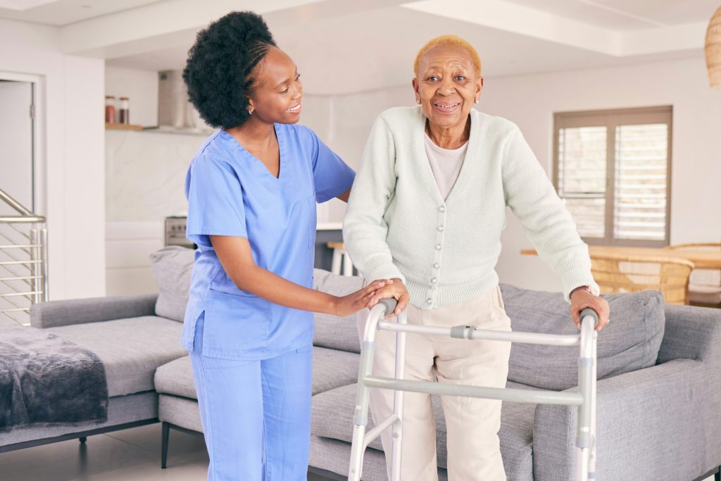 Nurse supporting an elderly woman using a walking frame at home