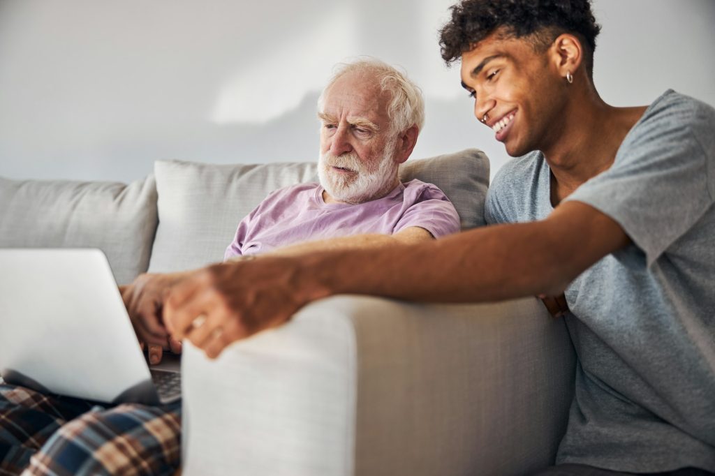 Older man using a laptop with his live-in carer