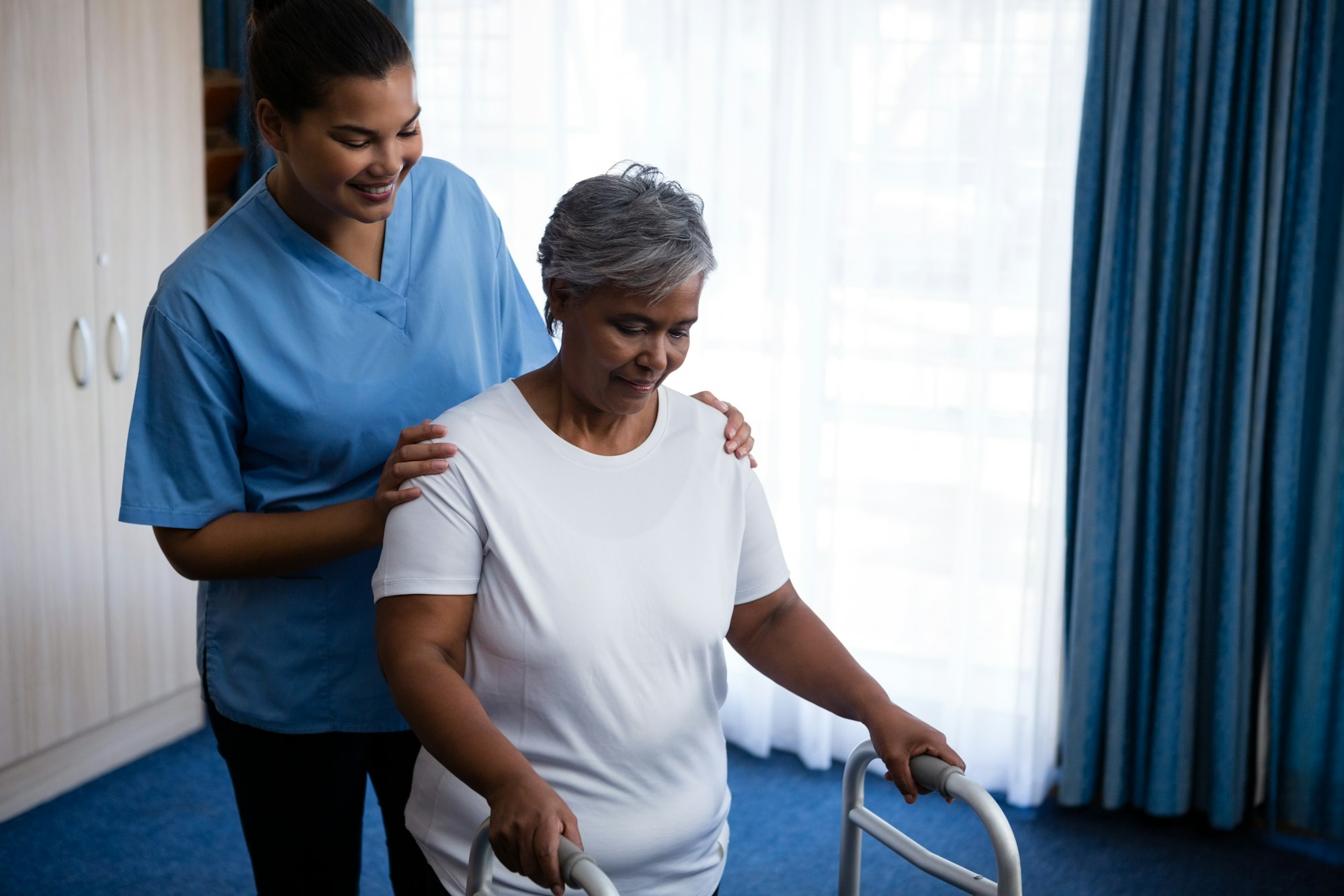 Nurse helping a senior woman walk with a walker