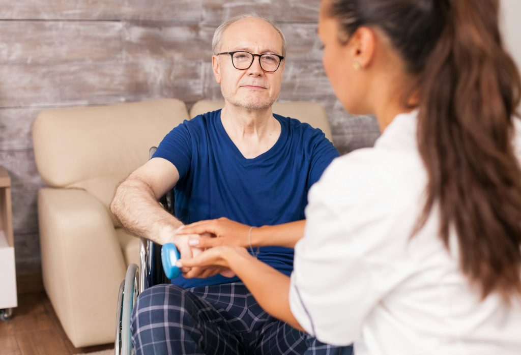 Carer helping a man with his recovery exercises